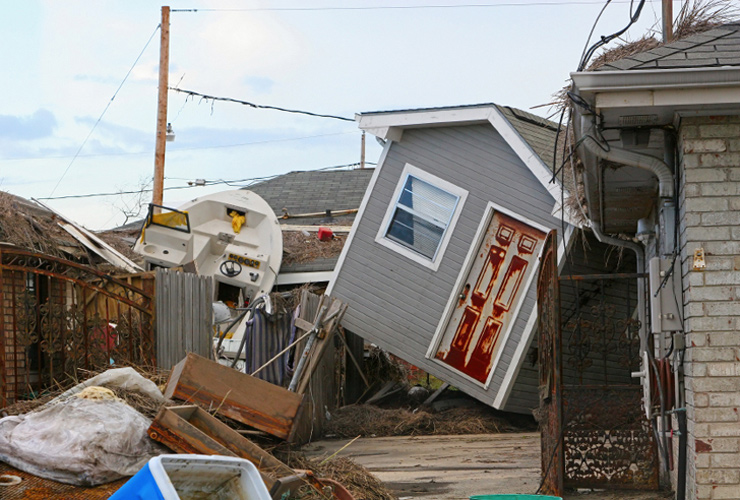 A driveway and back yard are littlered with debris after Hurricane Katrina. Sheds and boats piled on top of fences and house roofs.