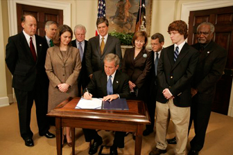 President George W. Bush signs S. 2634, the Garrett Lee Smith Memorial Act, in the Roosevelt Room Thursday, Oct. 21, 2004. The act authorizes the spending of $82 million for youth suicide prevention programs at college campus mental health centers. The legislation is named for Garret Smith, the son of Sen. Gordon Smith, R-Ore., and Sharon Smith, who are standing directly behind the President. Their son committed suicide Sept. 8, 2003. White House photo by Paul Morse