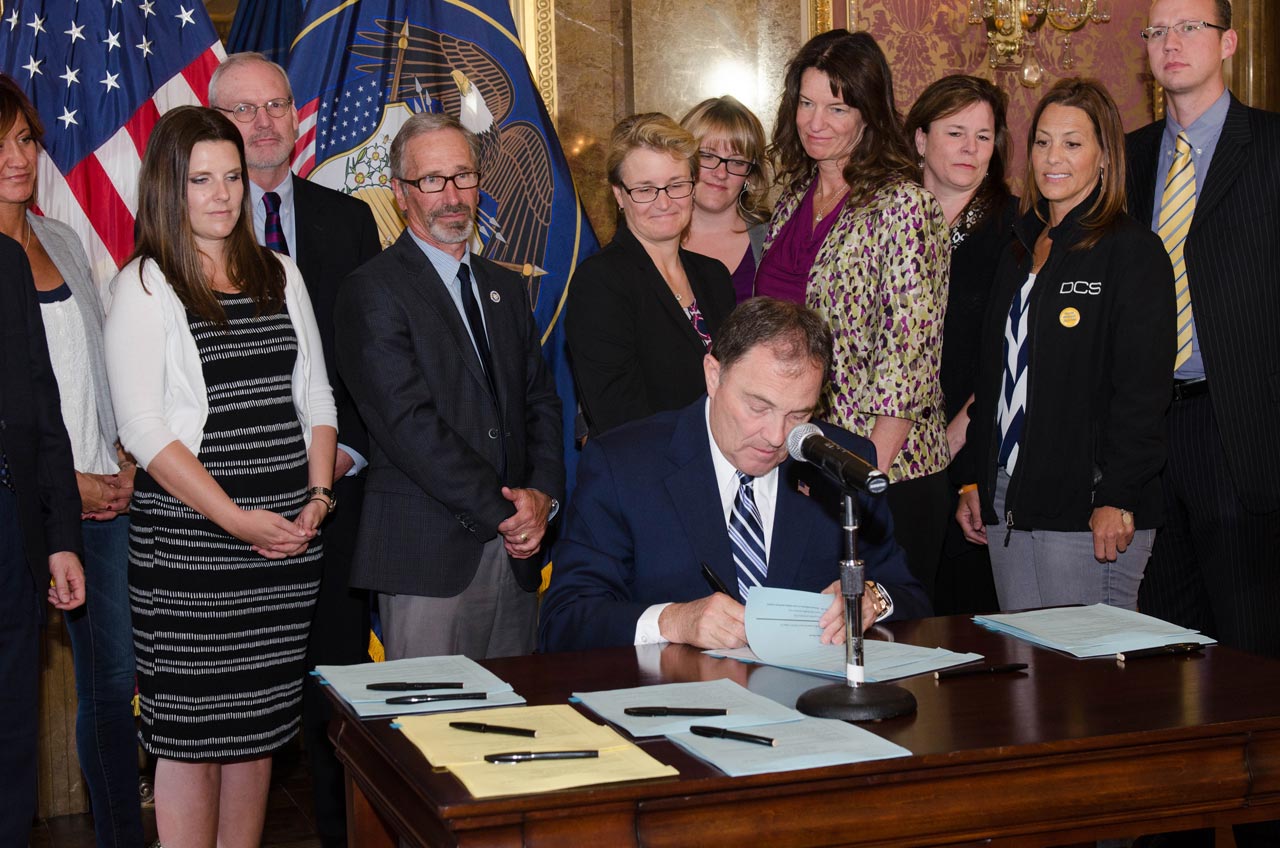 Utah Gov. Gary Herbert ceremoniously signed into law five bills related to the problem of suicide in Utah, while government administrators and citizens who have survived a suicide loss look on.